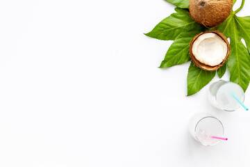 Coconut on green palm leaves with two glasses of fresh cocktail