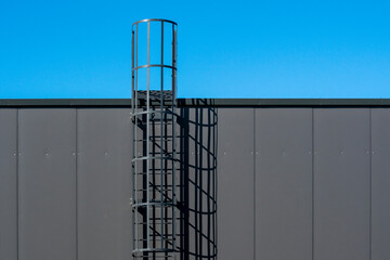 Steel ladder are on the side of the grey building wall