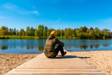 Fototapeta Young man sitting alone on the lake beach obraz