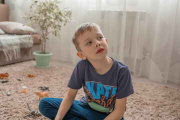 a little boy is watching TV sitting on the floor in the living room. The concept of the dangers of watching videos and TV shows for children for a long time