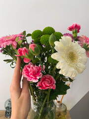 a bouquet of flowers in a vase, a hand holding a vase with flowers, flowers Rose, carnation, Daisy,