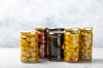 Olives in a glass jar on a concrete background. pitted green olives in jar.Pickled olives in glass jar. On a wooden background.Marinaded olives. Space for text.Space for copy. Vegan food.