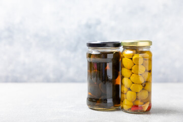 Olives in a glass jar on a concrete background. pitted green olives in jar.Pickled olives in glass jar. On a wooden background.Marinaded olives. Space for text.Space for copy. Vegan food.