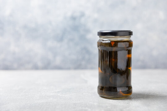 Olives in a glass jar on a concrete background. pitted green olives in jar.Pickled olives in glass jar. On a wooden background.Marinaded olives. Space for text.Space for copy. Vegan food.