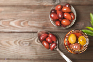 Olives in a glass jar on a brown wooden background. pitted green olives in jar.Pickled olives in glass jar. On a wooden background.Marinaded olives. Space for text.Space for copy. Vegan food.