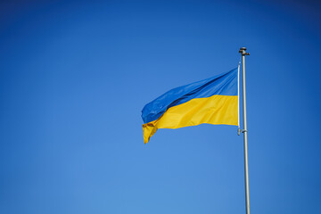 Yellow-blue flag of Ukraine in the wind against the background of a cloudless sky