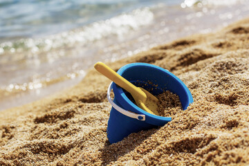 Sandy beach landscape with blue bucket and toy 