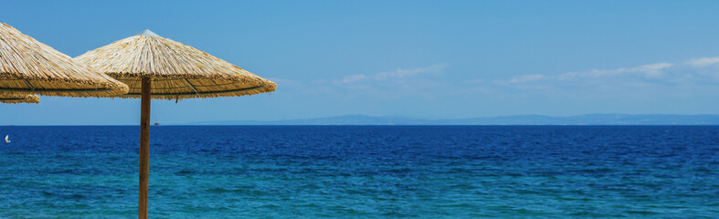 Escape to the coast for summer vacation under a parasol. Beach vacation summer scene. Blue sea horizon. Copy space.