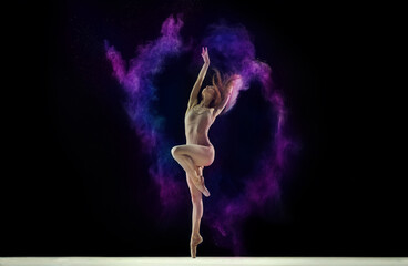 Obraz na płótnie Canvas Young tender girl, female ballet dancer in beige bodysuit dancing with colorful powder against black studio background. Concept of art, festival, beauty of dance, inspiration, youth, grace