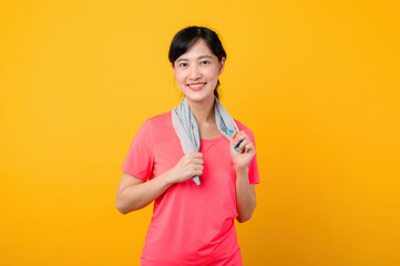 Portrait young asian sports fitness woman happy smile wearing pink sportswear and face towel doing exercise training workout against yellow studio background. wellbeing and healthy lifestyle concept.