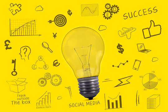 Large light bulb surrounded by smaller business icons and words drawn on a yellow paper