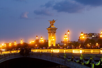 Fototapeta na wymiar Pont Alexandre III Bridge and illuminated lamp posts at sunset. 7th Arrondissement, Paris, France