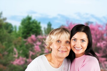 Mature woman hugging daughter on nature background