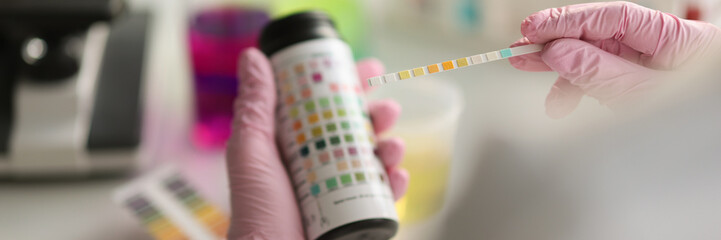 Doctor holds reagent strip for urinalysis closeup. Control analysis of urine in laboratory concept - obrazy, fototapety, plakaty