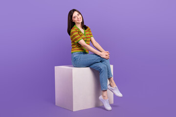 Full length photo of cheerful charming woman dressed striped cardigan sitting white platform isolated violet color background
