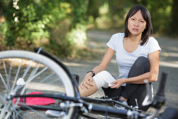 Fototapeta na wymiar sad woman fell off mountain bike bandaging her knee