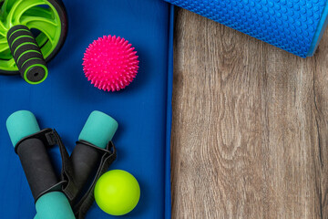 Obraz premium Sports equipment for fitness and yoga. Dumbbells, body shaping roller, spiky and smooth balls for acupuncture points on the body, roller for training the press and back on a yoga mat. Copy space