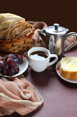 Brazilian breakfast. Black coffee, bread basket, sliced bread with butter and grapes.