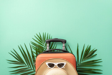 Dreaming of beach escape. Top view of a suitcase, beach gear, sunglasses, sunhat, and palm leaves...