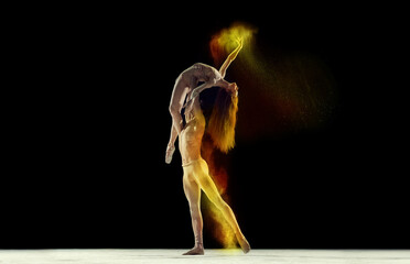 Graceful, beautiful couple, man and woman, ballet dancers performing against black studio background with colorful power explosion. Concept of art, festival, beauty of dance, inspiration, youth
