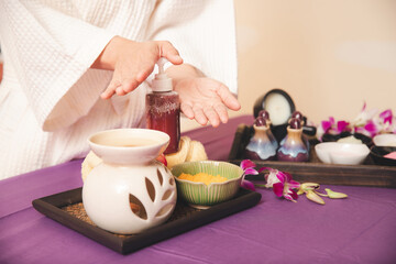 Woman push the essential oil bottle or moisturizer, lotion, cream with skin care products. Sea salt, essential oil, moisturizer, lotion, cream and treatment body scrubs in basket.