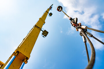 The hydraulic cylinders of an offshore oil rig crane are using four strong slings to lift large loads with four corner sling handles.