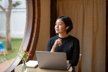 Freelance businesswoman sitting in front of her considering work at cafe, thinking new project work...