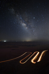 the milky way over a curvy road with light trails of a car  near Mizpe Ramon - Israel 