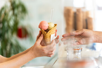 A man is serving an ice cream cone of various flavors to a woman