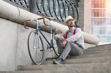 Adult hipster man with retro fixed gear bicycle on stairway in the downtown