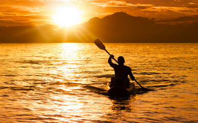 Silhouette of man at sunset paddling in his kayak on the coast of Brazil, Tabatinga beach in São...