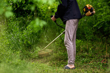Caucasian Gardener working man Manual hand grass cutter  Weed Cutter or Power Weeder or Brush Cutter Lawn Mowe  Gasoline close up.