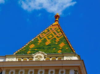 steep sloped enamel coated clay tile Mansard roof with colorful orange, yellow and green geometric...