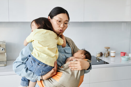 Asian young mother babysitting with her two children at home