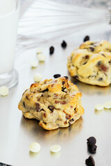Large cookies with milk and chocolate chips on a table.