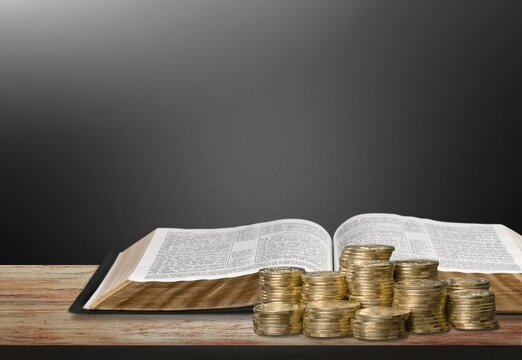 Holy Bible book and stack of coins