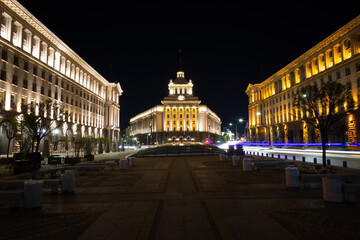 Building of the national assembly of Bulgaria in the city of Sofia illuminated at night, with the headlights of cars passing in long exposure