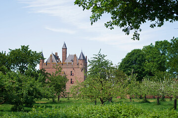 Fototapeta na wymiar Medieval castle Doornenburg between trees in Doornenburg in the Netherlands with a blue sky with some clouds