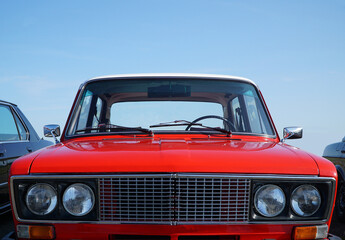 red retro soviet car on a blue sky in car show