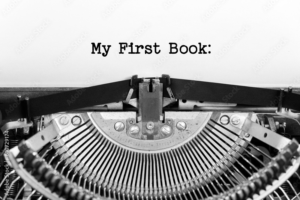 Fototapete My First Book phrase close up being typing and centered on a sheet of paper on old vintage typewriter mechanical