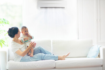 Mother and child with air conditioner remote