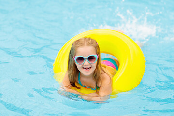 Child in swimming pool on toy ring. Kids swim.