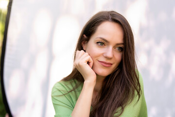 Portrait of young woman with beautiful green eyes and brunette hair sitting at sunglight