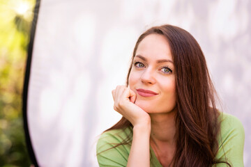 Portrait of young woman with beautiful green eyes and brunette hair posing at sunglight