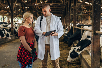 A vet speaks to a female farmer in a barn about th cows.