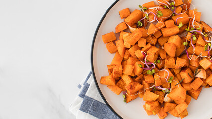 Baked sweet potato slices in a plate on the table. Healthy eating. Vegan dish. Copy space