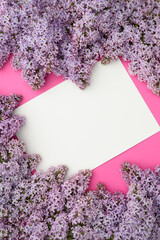 Layout of purple lilac flowers on a pink background,mock up in the center.Natural flower arrangement,flat lay, top view.