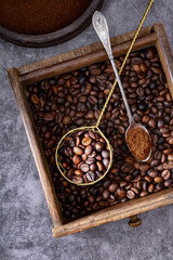 Roasted coffee beans in a wooden bowl and a metal teaspoon