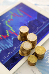 Coins and tablet computer with diagrams of exchange rates, closeup