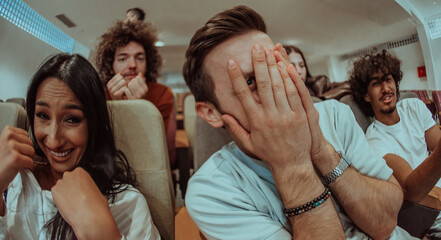 A diverse group of friends with terrified expressions together in a cinema to watch a horror film, experiencing a mix of fear, excitement, and laughter, as they collectively navigate through